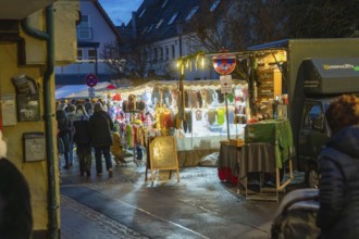 Night market with illuminated stalls and people in cold weather, Aidlingen Christmas market,