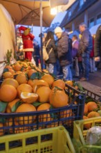 Fresh oranges in boxes in front of curious market visitors in the evening, Aidlingen Christmas