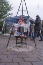 A cauldron over an open fire at a Christmas market with people and Christmas decorations, Aidlingen