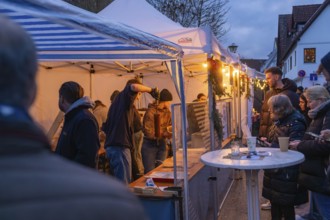 People at a market stand at dusk enjoying the festive atmosphere, Aidlingen Christmas Market,