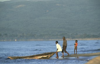 Men letting dugout into water, boy, Lake Malawi, Kande, Malawi, Africa, July 2000, vintage, retro,