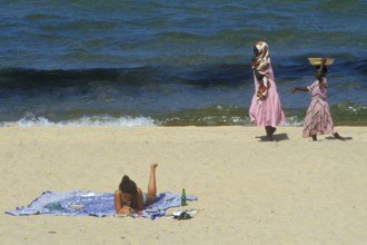 Tourist in bikini and traditionally dressed local woman at Kande Beach on Lake Malawi, Malawi,