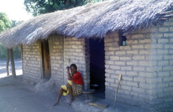 Woman sitting in front of a house in a village near Kande on Lake Malawi, Malawi, Africa, July