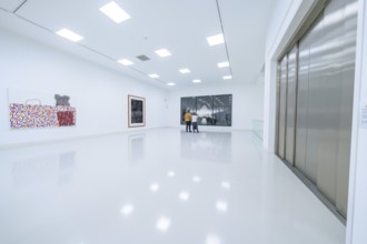 Two people look at works of art in a modern, bright exhibition room, Open Horizons exhibition,