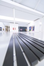 Minimalist bench in a modern gallery with works of art, flooded with light, Open Horizons