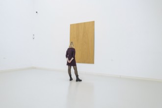 Woman looking at a large, simple, wooden work of art in a minimalistic space, Open Horizons