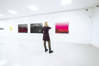 Woman looking at abstract paintings in a bright, modern art gallery, Open Horizons exhibition,
