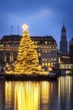 The decorated and illuminated Alster fir tree on the Inner Alster with reflections on the water in