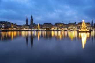 The decorated and illuminated Alster fir tree on the Inner Alster with reflections on the water in