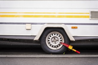 Caravan wheel with yellow-red parking claw parked on a street, Wuppertal, Germany