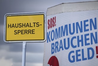 (photo montage) Town entrance sign with the inscription HOUSEHOLD LOCK next to a poster with the