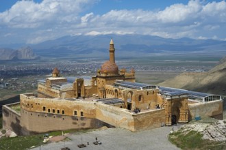 An imposing historic fortress in a mountainous landscape under blue sky with clouds, Ishak Pasha