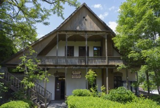 Traditional wooden house with veranda surrounded by green trees and natural ambiance, Old Town,