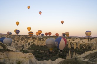 Hot air balloons float over a rocky landscape at dawn, bright colors create a peaceful atmosphere,