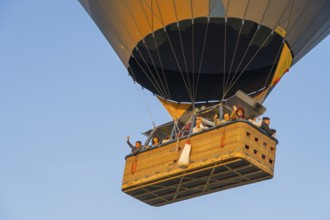 A hot-air balloon basket full of people floats in the warm morning light, symbolizing freedom and