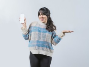 Smiling asian girl showing phone screen isolated. Beautiful asian young woman showing an