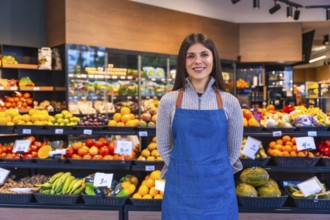 Greengrocer woman smiling and looking at the camera while standing proudly in a supermarket,