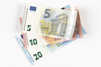 Stacked euro banknotes in denominations of 5, 10 and 20 on a white background
