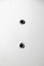 Two drill holes with dowels in a white wall