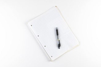 Notebook with checkered pages and a black ballpoint pen on a white background