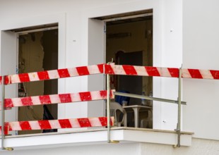 Balcony secured with red and white striped slats at the construction site of a house, Nazare,