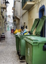 Green trash bins in a small alley in Nazare, Portugal