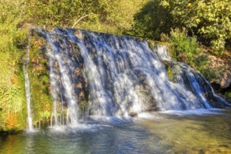 Fascinating waterfall flowing over green moss rocks into a natural basin, El Kelaa wild stream in
