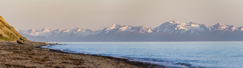 Boat on Anchor Point beach on Cook Inlet in the evening light, snowy mountain peaks of the Kenai