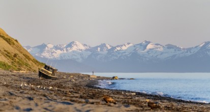 Boat on Anchor Point beach on Cook Inlet in the evening light, snowy mountain peaks, Anchor River