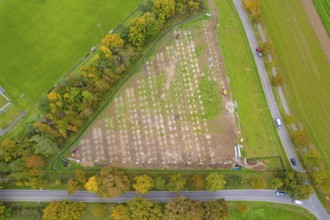 Aerial view of a field with construction next to a road surrounded by autumn trees, PV