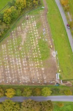 Aerial view of a large rectangular field with construction activities surrounded by autumn trees,