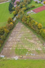 Parceled green area in triangle shape, surrounded by trees and infrastructural facilities, PV