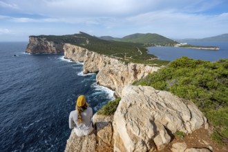 Tourist sitting on the edge of a steep cliff, view of steep cliffs by the sea, coastal landscape,