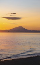 View of Cook Inlet on white mountain peaks of Mount Redoubt at sunset, picturesque golden light of