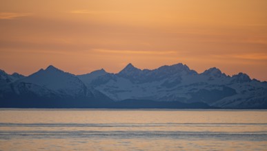 View of Cook Inlet on white mountain peaks of the Aleutian Range, picturesque golden light of the