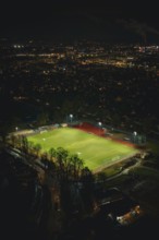 Illuminated soccer field in an urban area at night with glowing city lights, Sindelfingen,