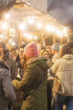 Sociable people in winter clothes at an atmospheric Christmas market, Christmas market 2025,