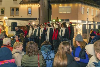 A choir sings on a busy street in front of an audience in wintry weather, Christmas market 2025,
