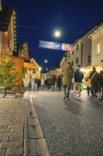People stroll at night through an illuminated pedestrian zone with a festive atmosphere, Christmas