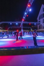 Colourful lights on an ice rink at night, people skating and friendly togetherness, Christmas