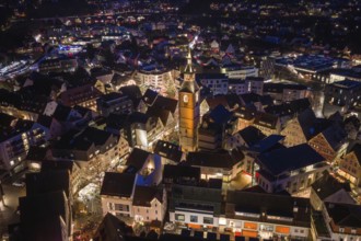 Aerial view of an illuminated city at night dominated by a large church surrounded by festively