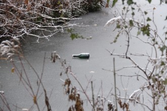 Symbolic picture of garbage in nature, bottle on frozen lake, winter, Germany