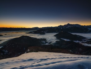Alpine panorama at dawn in winter, fog in the valley, partly illuminated from below, Untersberg,