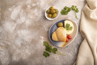 Smoked Mozzarella cheese, with tomatoes and olives on brown concrete background and linen textile,
