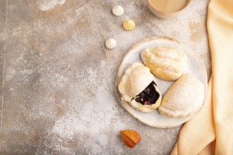 Glazed Pies with blueberry jam on brown concrete background and orange linen textile, cup of