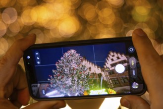 In the evening, a visitor to the Frankfurt Christmas market photographs the glowing Mrs. Holle