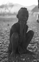 Himba child sitting on ground, traditional Himba village, Kaokoveld, Kunene, Namibia