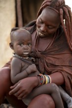 Baby in the arms of a Himba woman, traditional Himba village, Kaokoveld, Kunene, Namibia