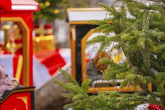 A decorated Christmas tree with lights next to a brightly decorated toy train, Sindelfingen,