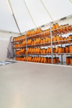 A room with shelves full of orange boots in a tidy tent, Sindelfingen, Böblingen district, Germany